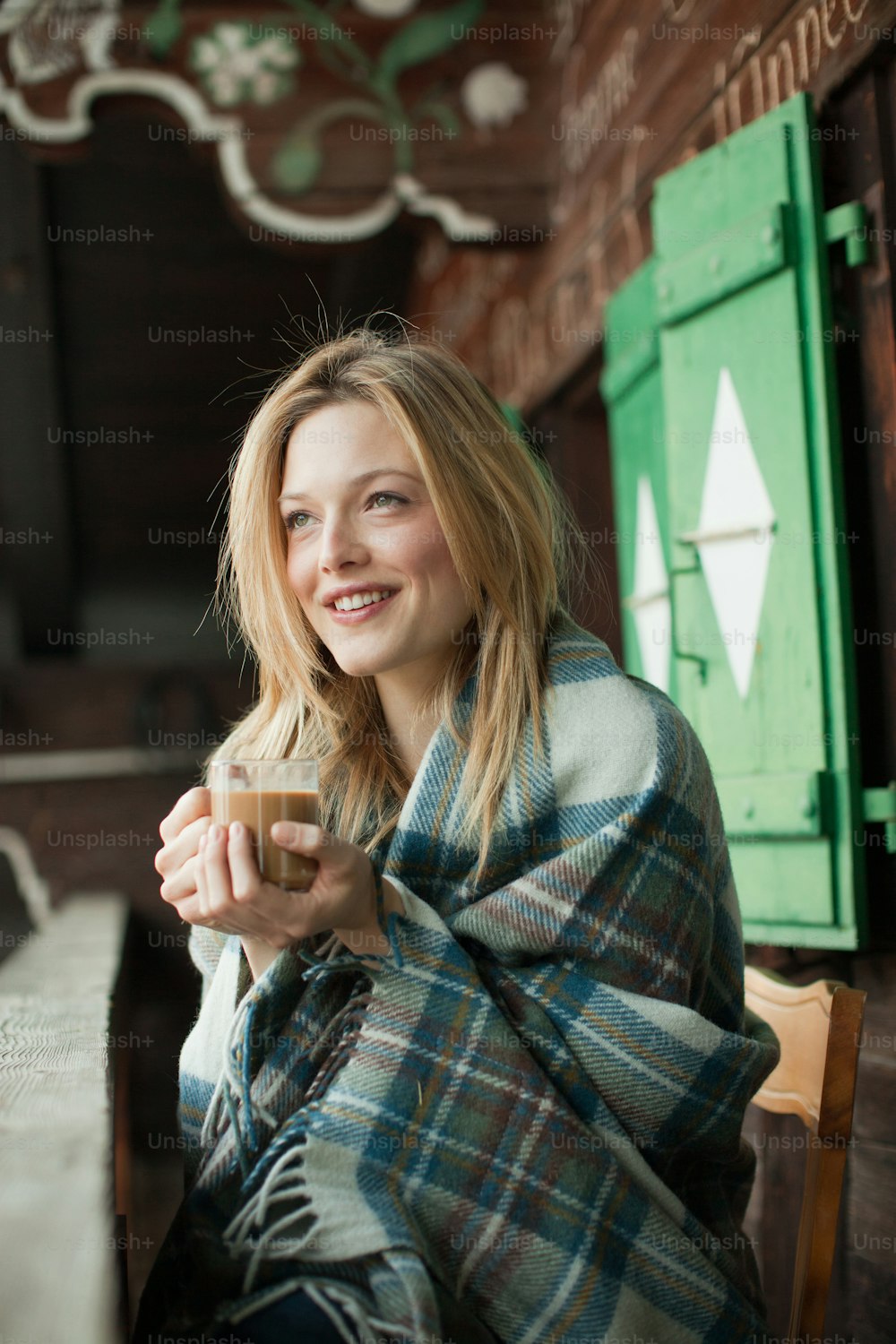 a woman sitting on a chair wrapped in a blanket