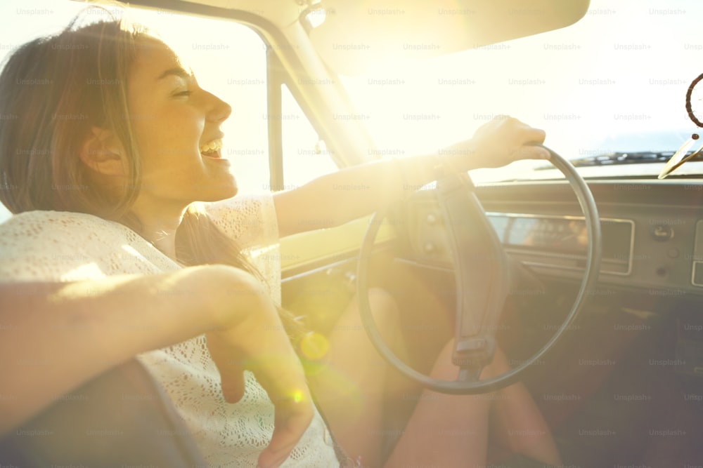 도로 여행을 하는 동안 차를 운전하는 행복 한 젊은 여자