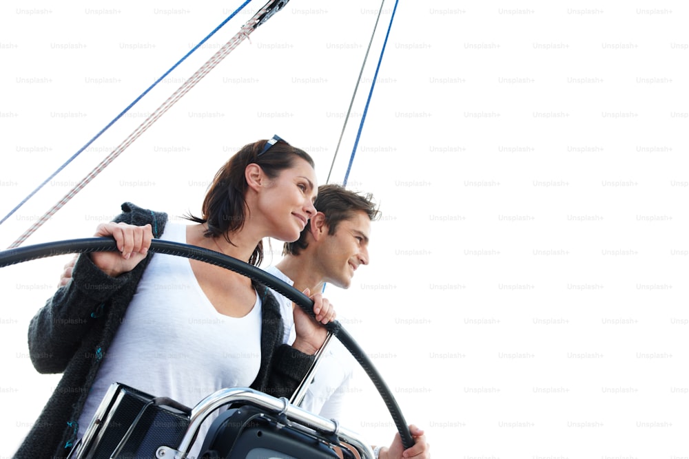 A young couple staring off into the distance while standing at the wheel of a boat