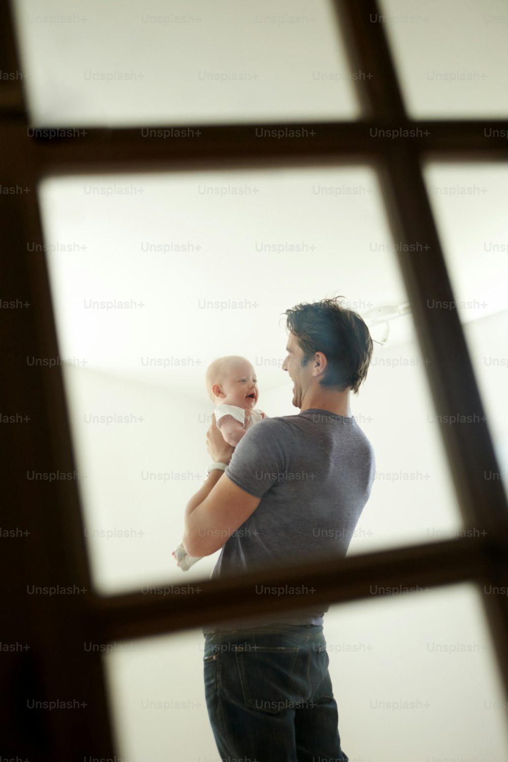 A candid image of a loving father holding his son shot through a window
