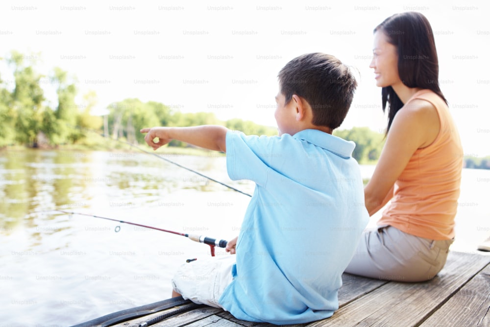 Young Asian mother and son sitting on a jetty and fishing together