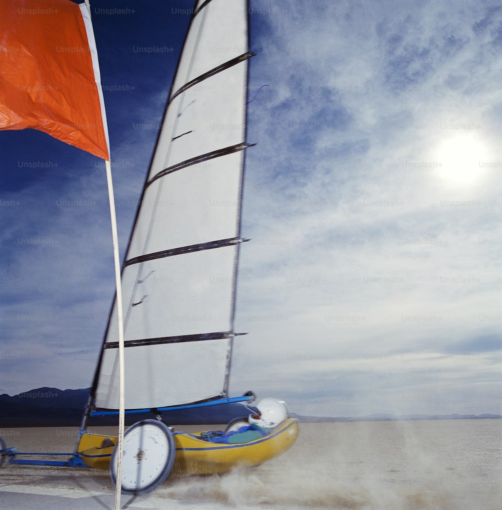 una piccola barca a vela sulla spiaggia con una bandiera