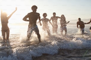 a group of people standing in the water at the beach
