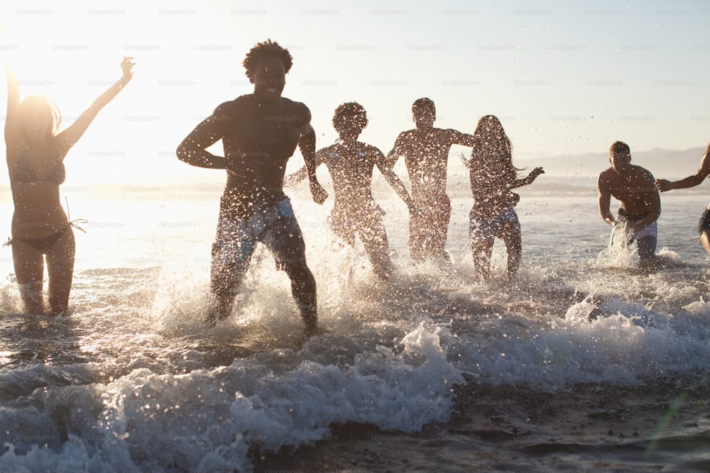 a group of people standing in the water at the beach