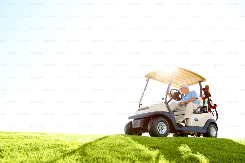 A senior retired couple drivig a golf cart on a golf course