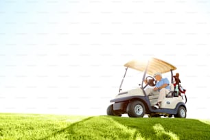 A senior retired couple drivig a golf cart on a golf course