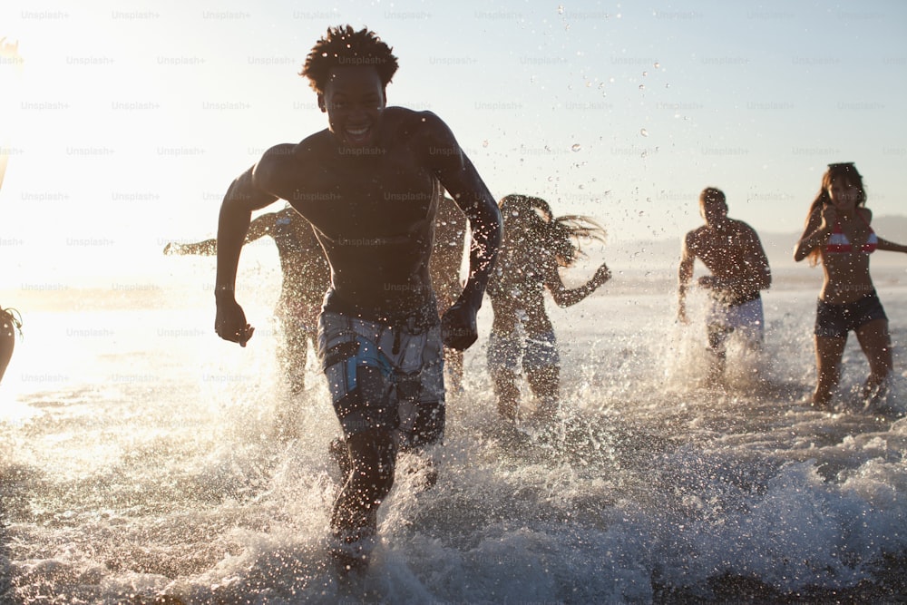 a group of people running into the ocean