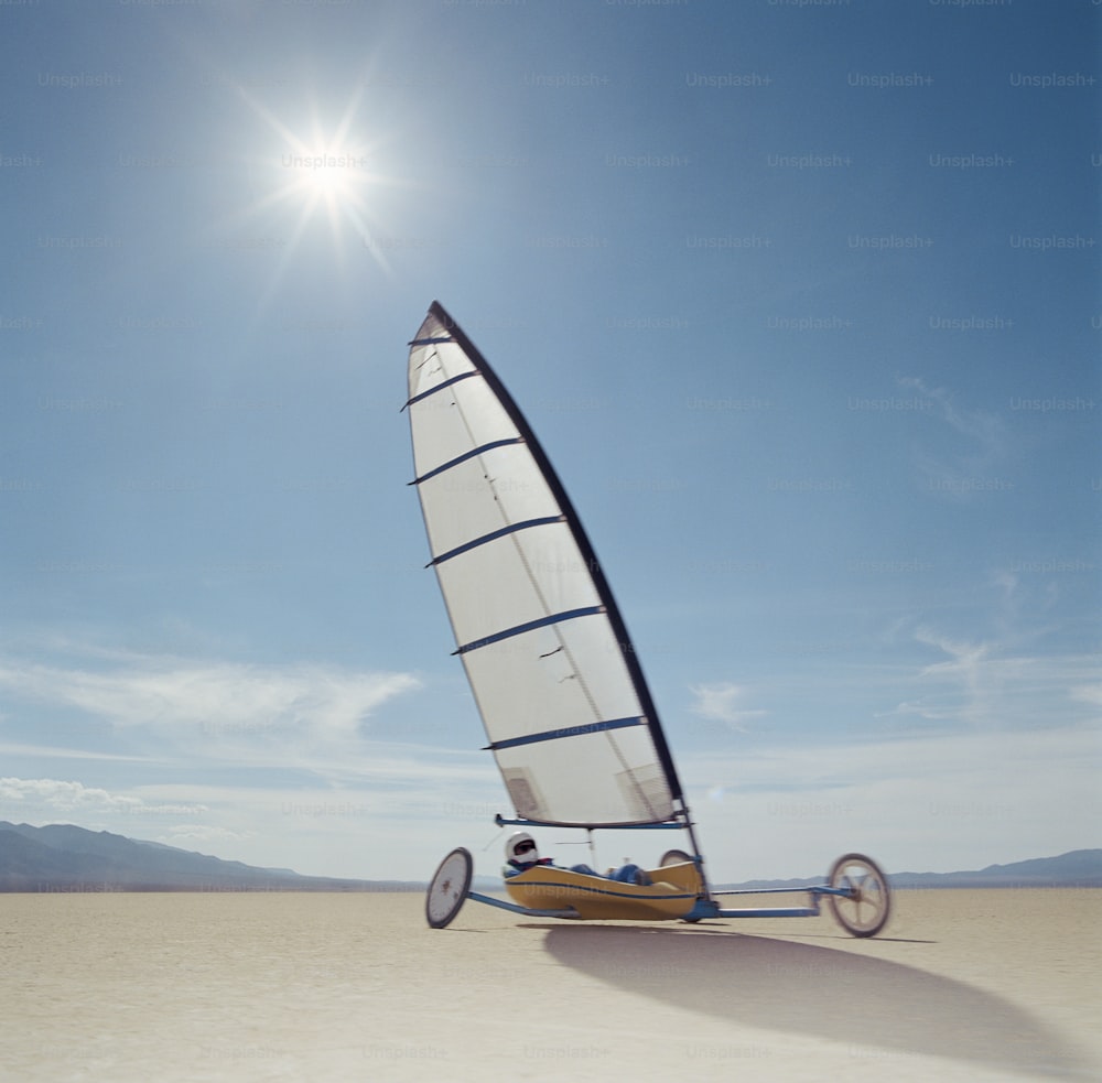 a small sailboat on a sandy beach under a blue sky