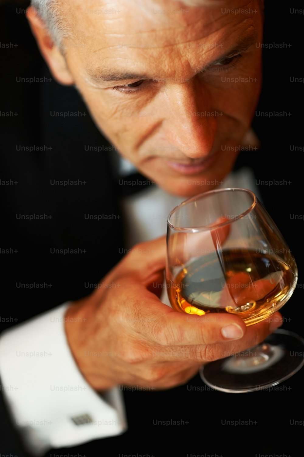 Ein Mann im Smoking hält ein Glas Wein in der Hand