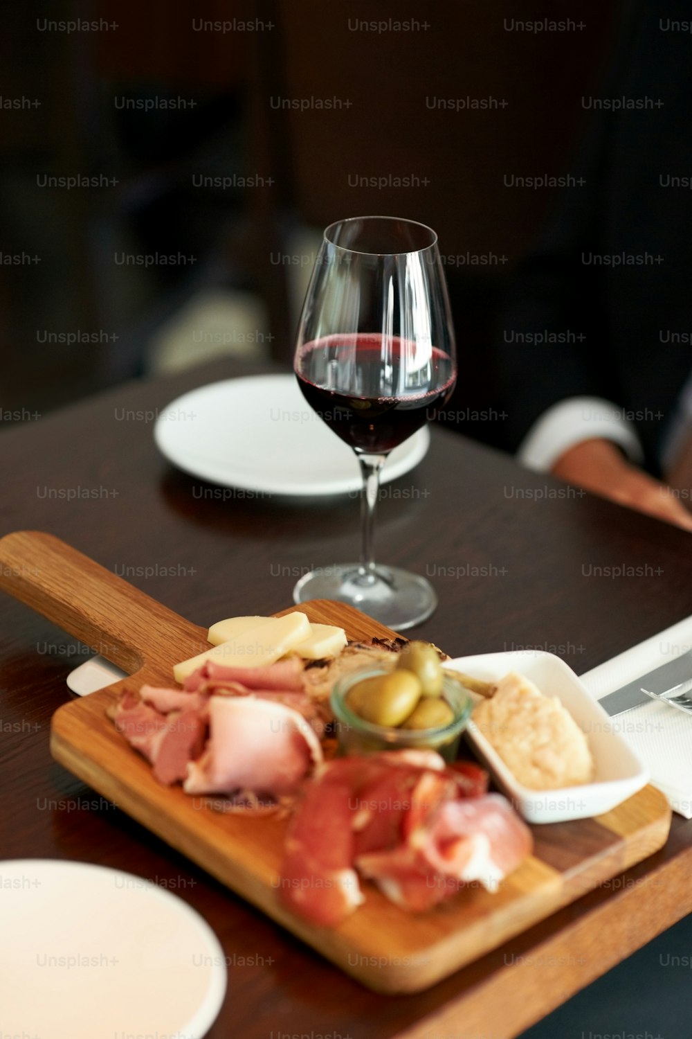 a wooden cutting board topped with food next to a glass of wine