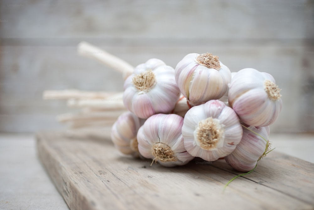 a bunch of garlic sitting on top of a wooden cutting board