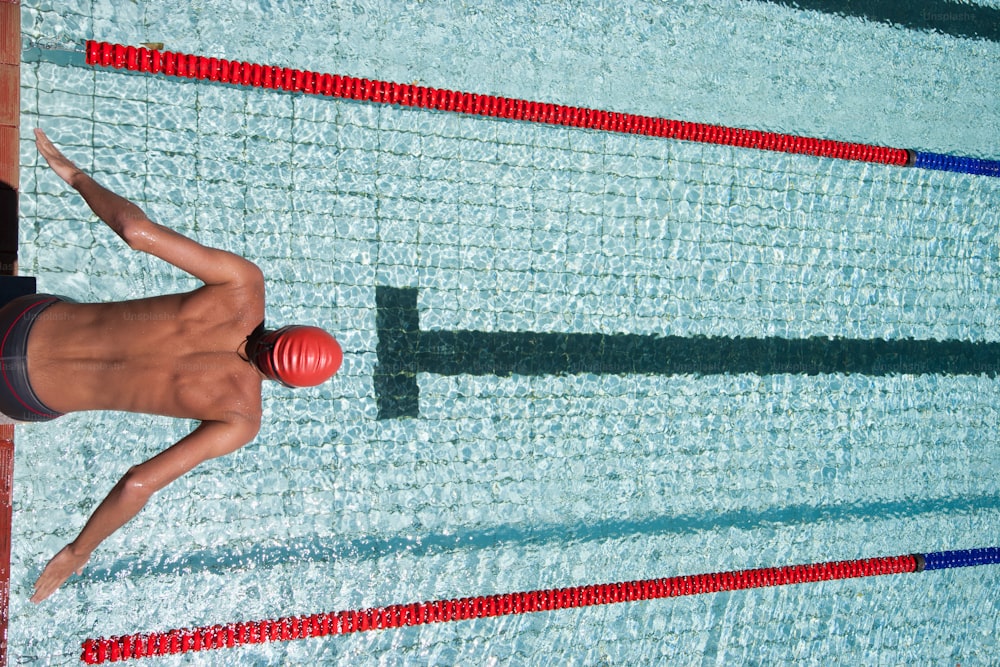 Un uomo in piedi accanto a una piscina con in mano una palla rossa