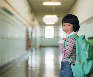 a young girl with a backpack in a hallway
