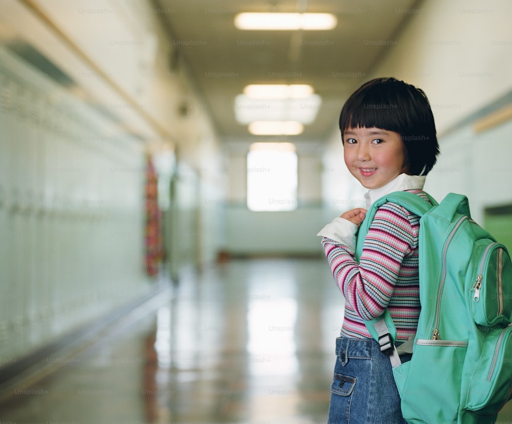 a young girl with a backpack in a hallway