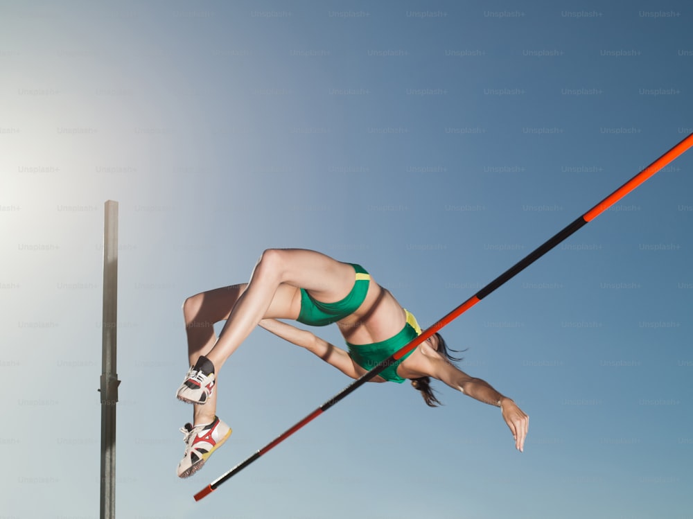 a woman in a green bikini doing a trick on skis