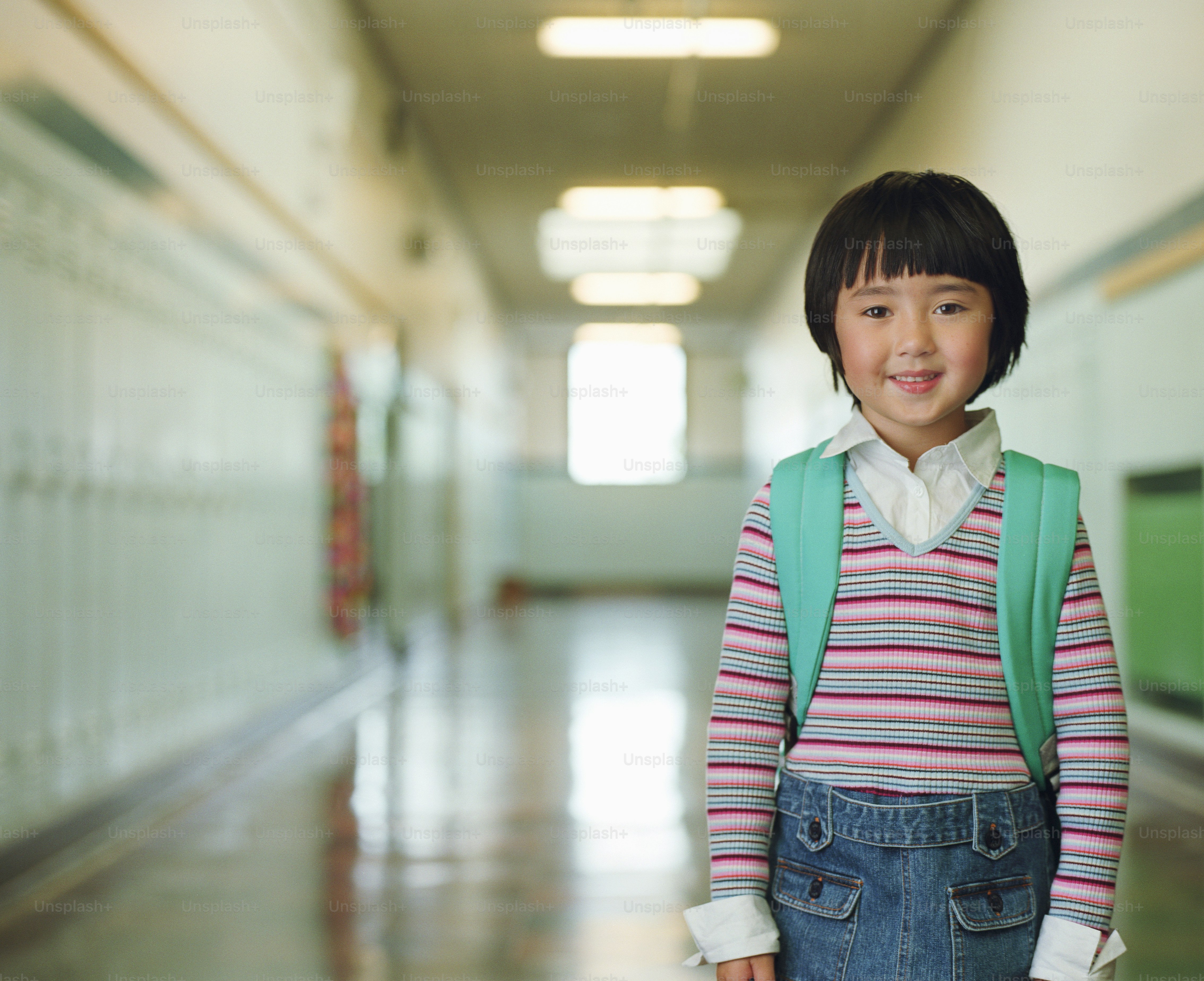 Une petite fille debout dans un couloir avec un sac à dos
