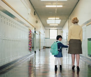 a woman and a child are walking down a hallway