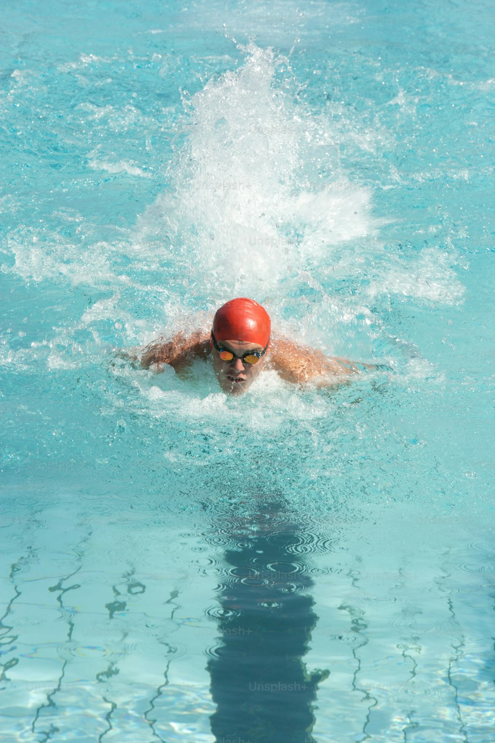 Un hombre nadando en una piscina con una pelota roja