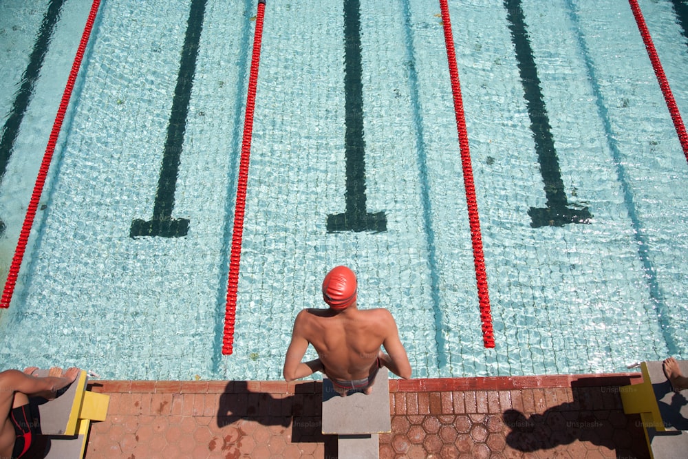 a man sitting on a bench next to a swimming pool