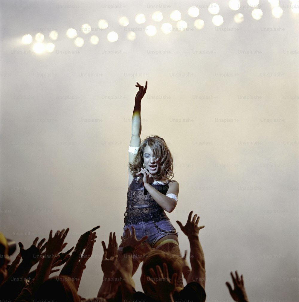 Una mujer parada en la cima de un escenario con los brazos en el aire