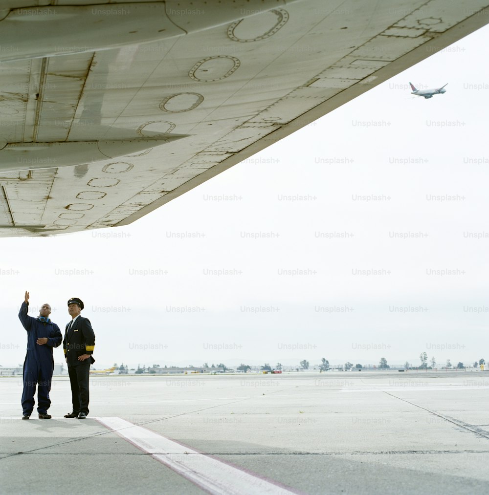 a couple of men standing next to an airplane