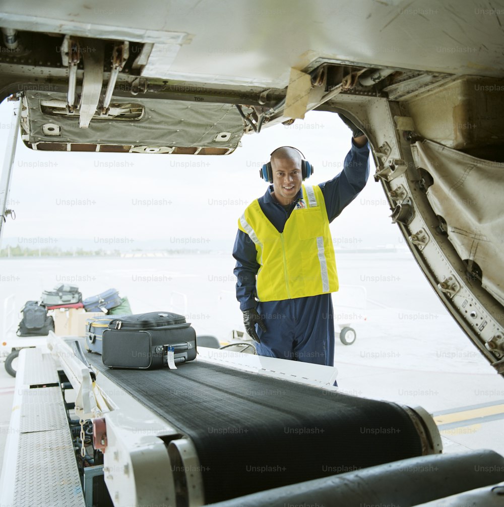 a man in a yellow vest standing next to an airplane