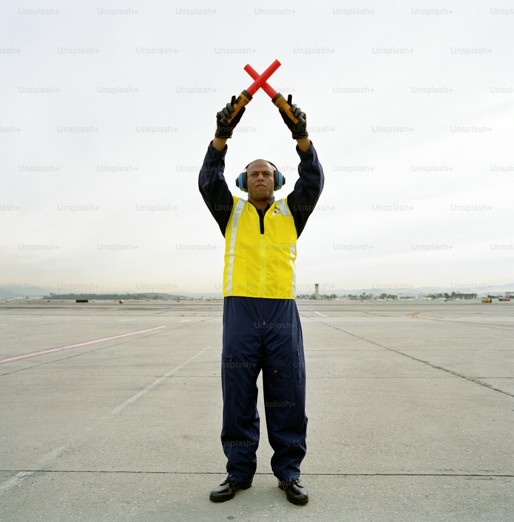 a man in a yellow vest holding a red object in the air