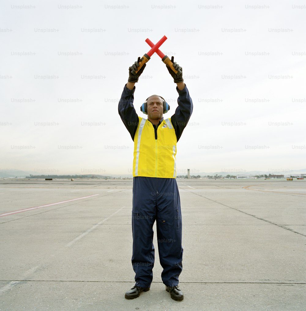 um homem de colete amarelo segurando um objeto vermelho no ar