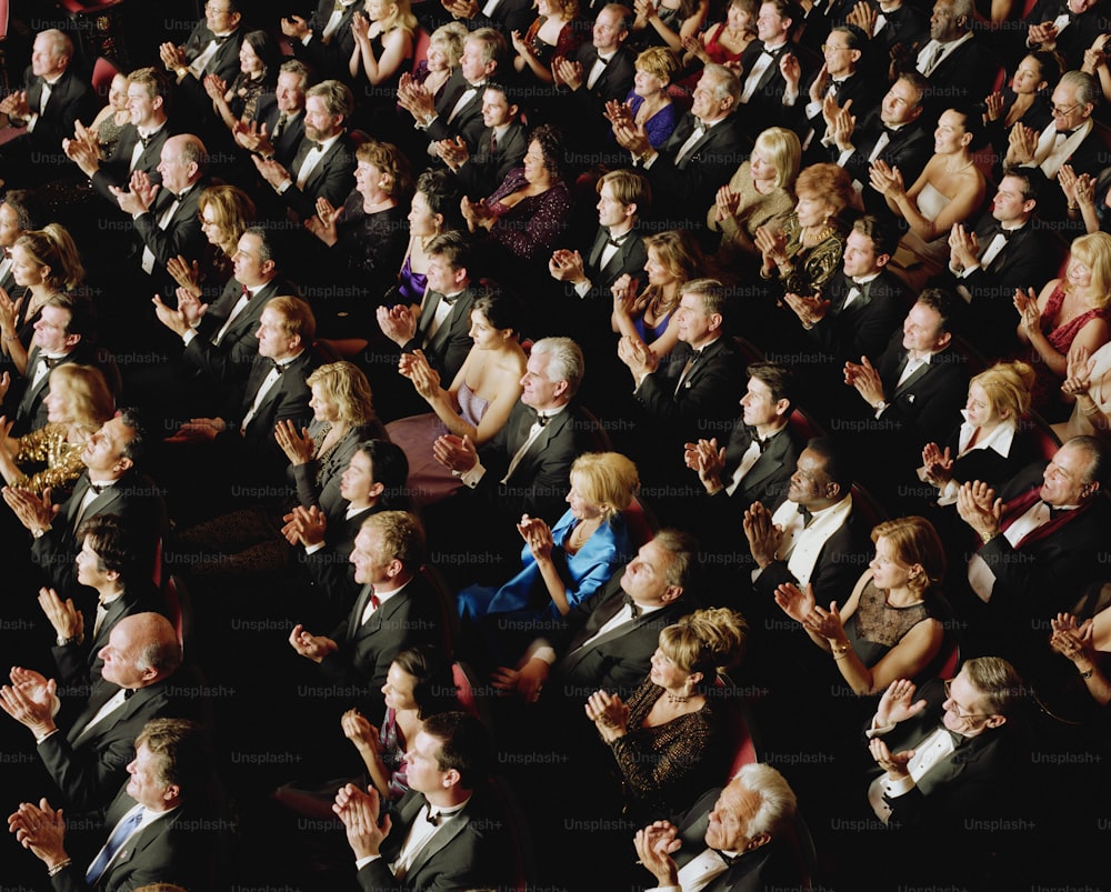 uma multidão de pessoas de terno e gravata batendo palmas