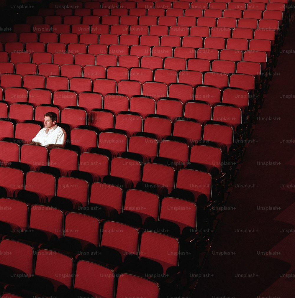 a woman is sitting in a row of red chairs