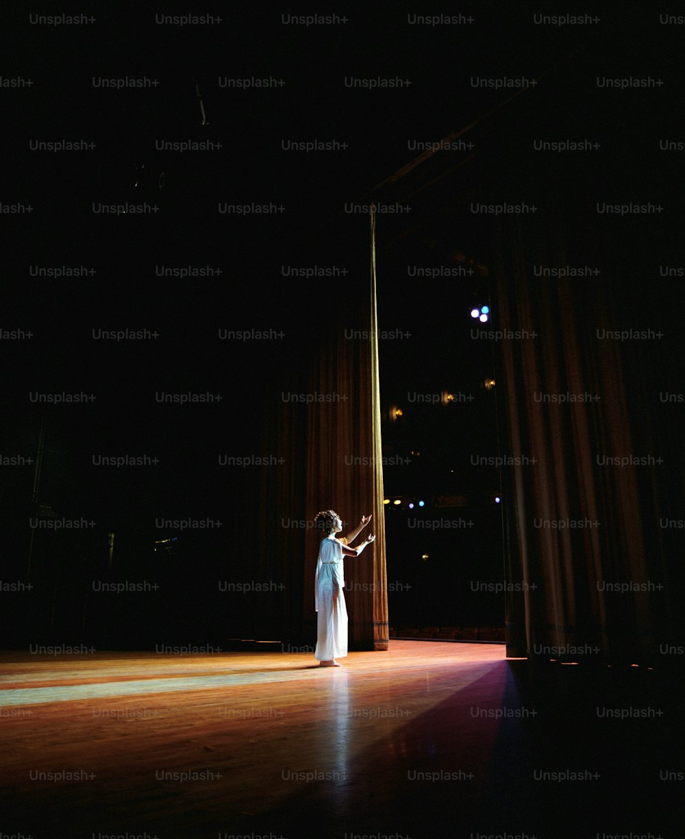 uma mulher em um vestido branco em pé em um palco