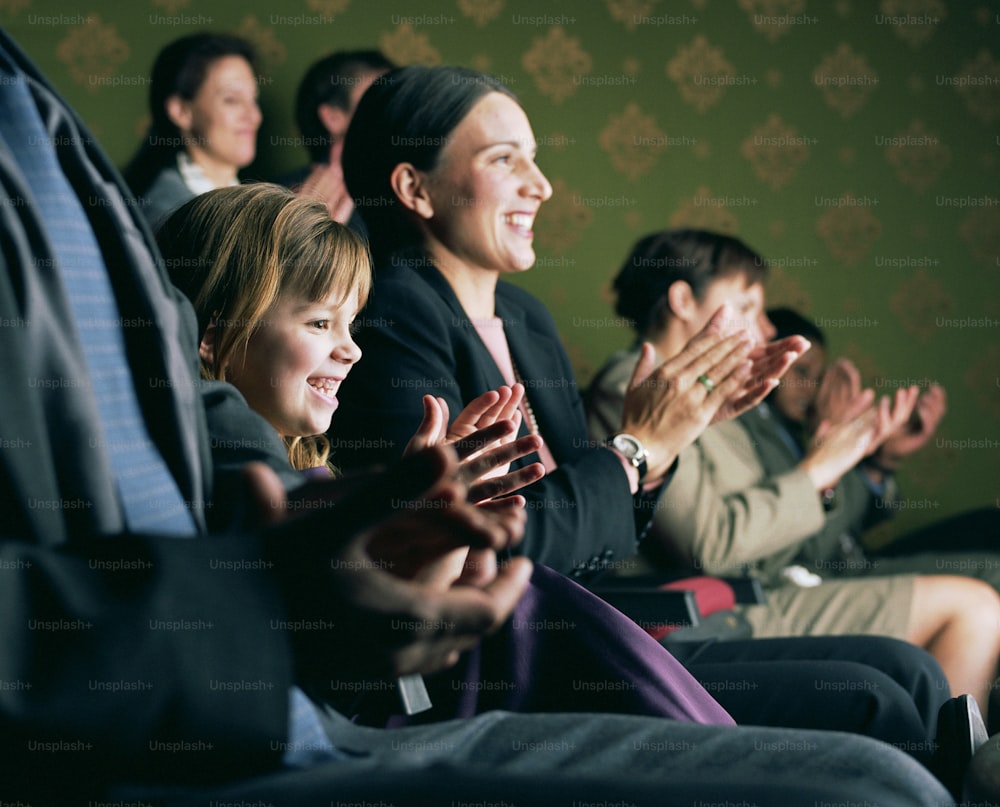 a group of people sitting in a row clapping