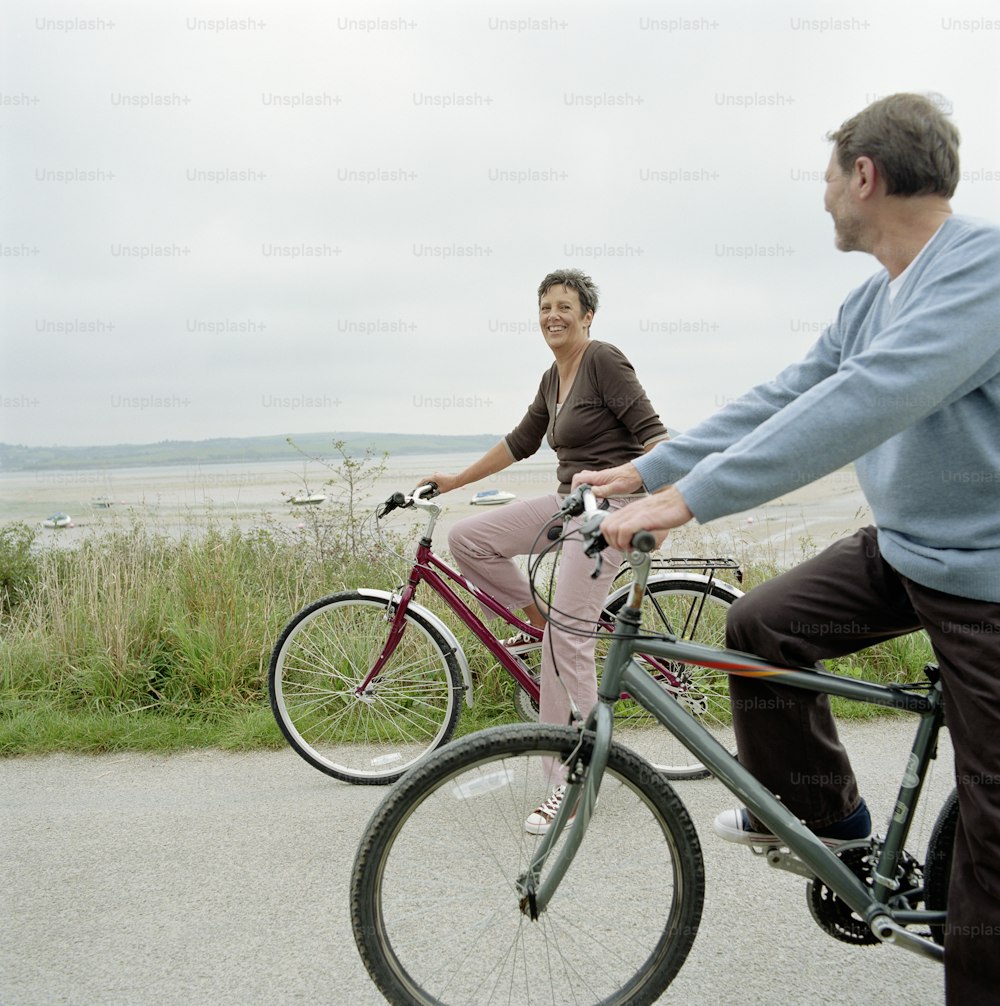 um homem e uma mulher andando de bicicleta em uma estrada