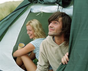 a man and a woman sitting inside of a tent