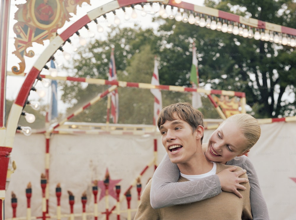 a boy and a girl hugging in front of a carnival ride