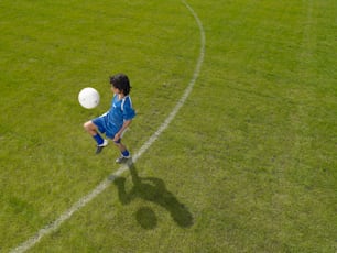 a young boy kicking a soccer ball across a field
