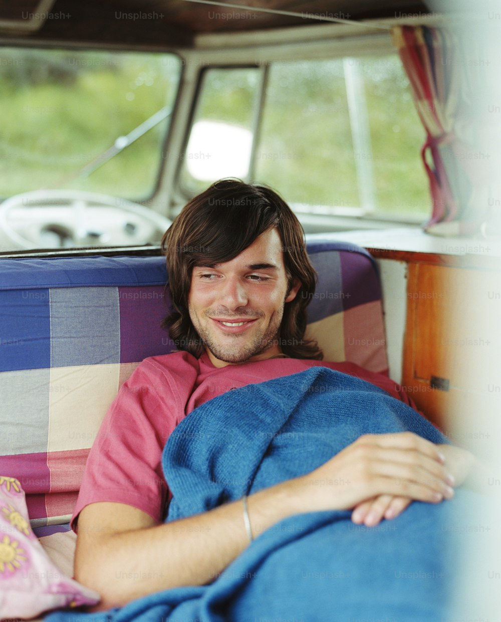 a man laying in the back of a truck under a blanket