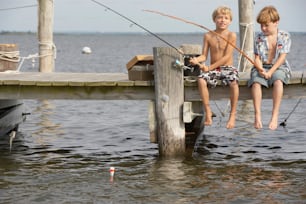 two young boys sitting on a dock fishing
