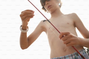 a shirtless boy holding a fishing pole
