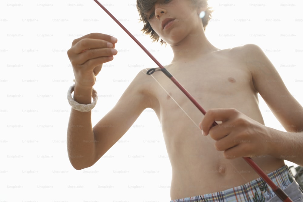 a shirtless boy holding a fishing pole