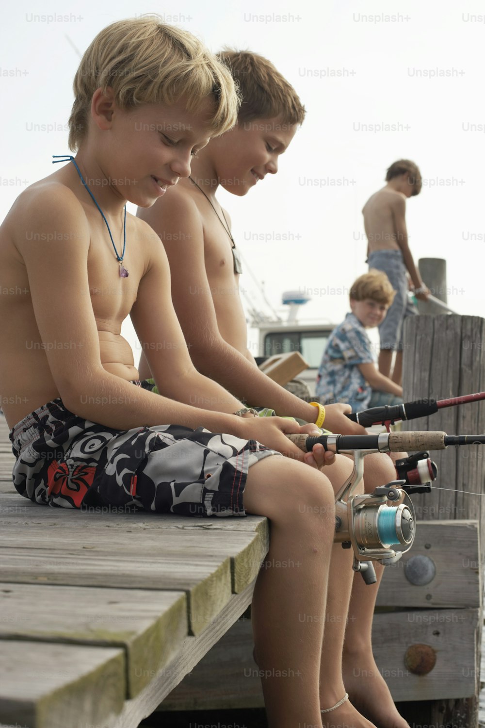 two boys sitting on a dock with fishing rods