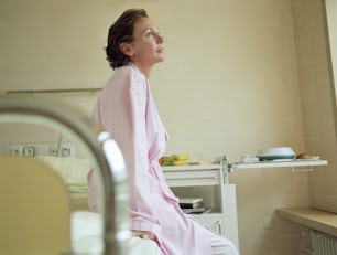 a woman in a pink robe sitting on a bed