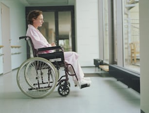Une femme en fauteuil roulant regardant par une fenêtre