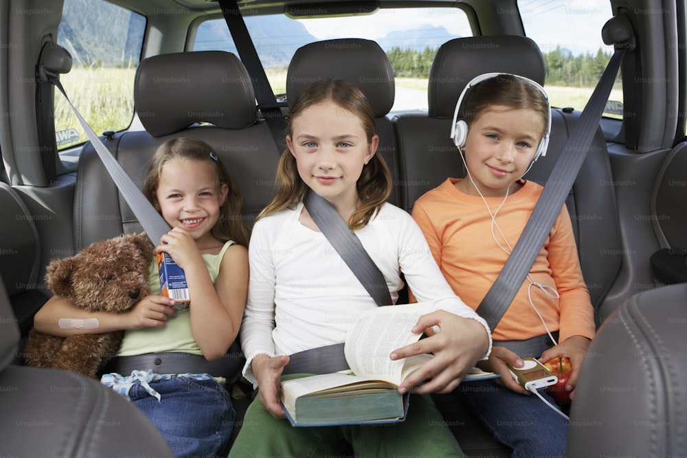 Tres chicas jóvenes sentadas en la parte trasera de un coche