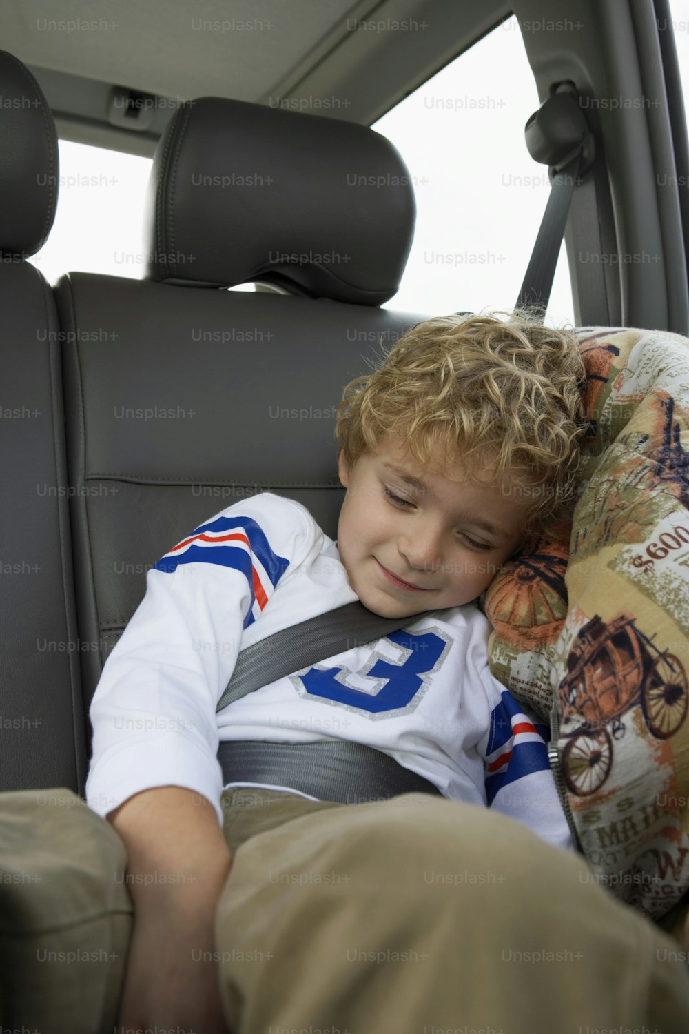 a young boy sitting in the back seat of a car