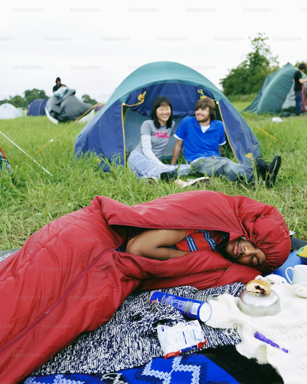 um homem dormindo em um saco de dormir em um campo
