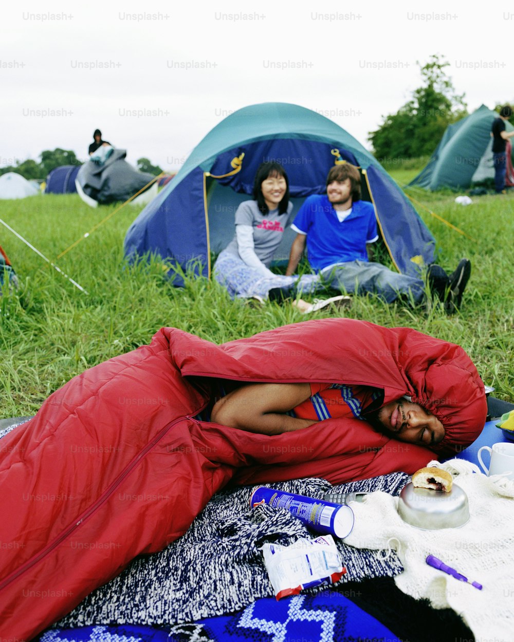 a man sleeping in a sleeping bag in a field