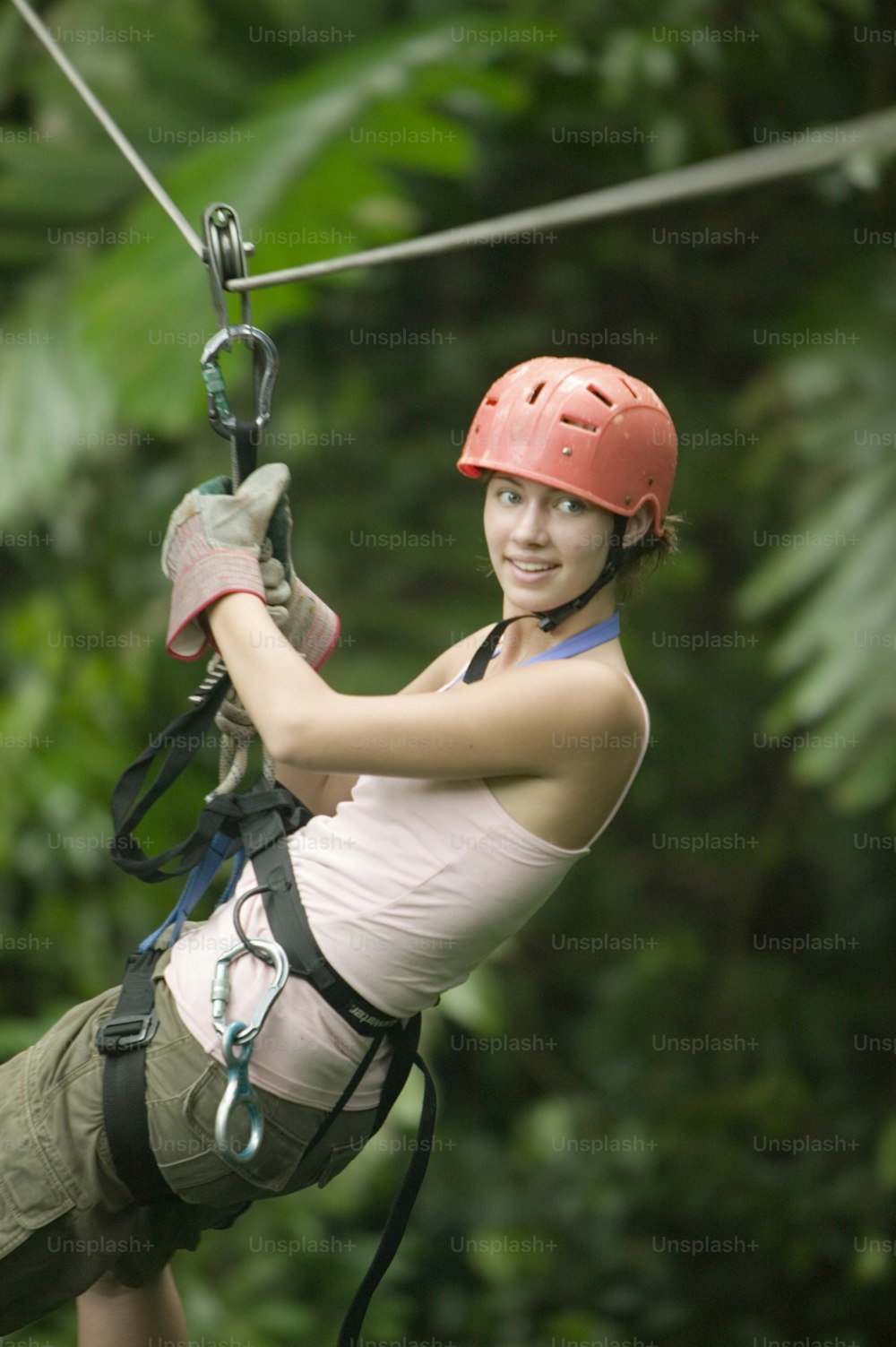 a woman in a helmet is zipping through the jungle