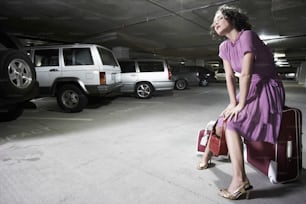 a woman in a parking garage with her luggage
