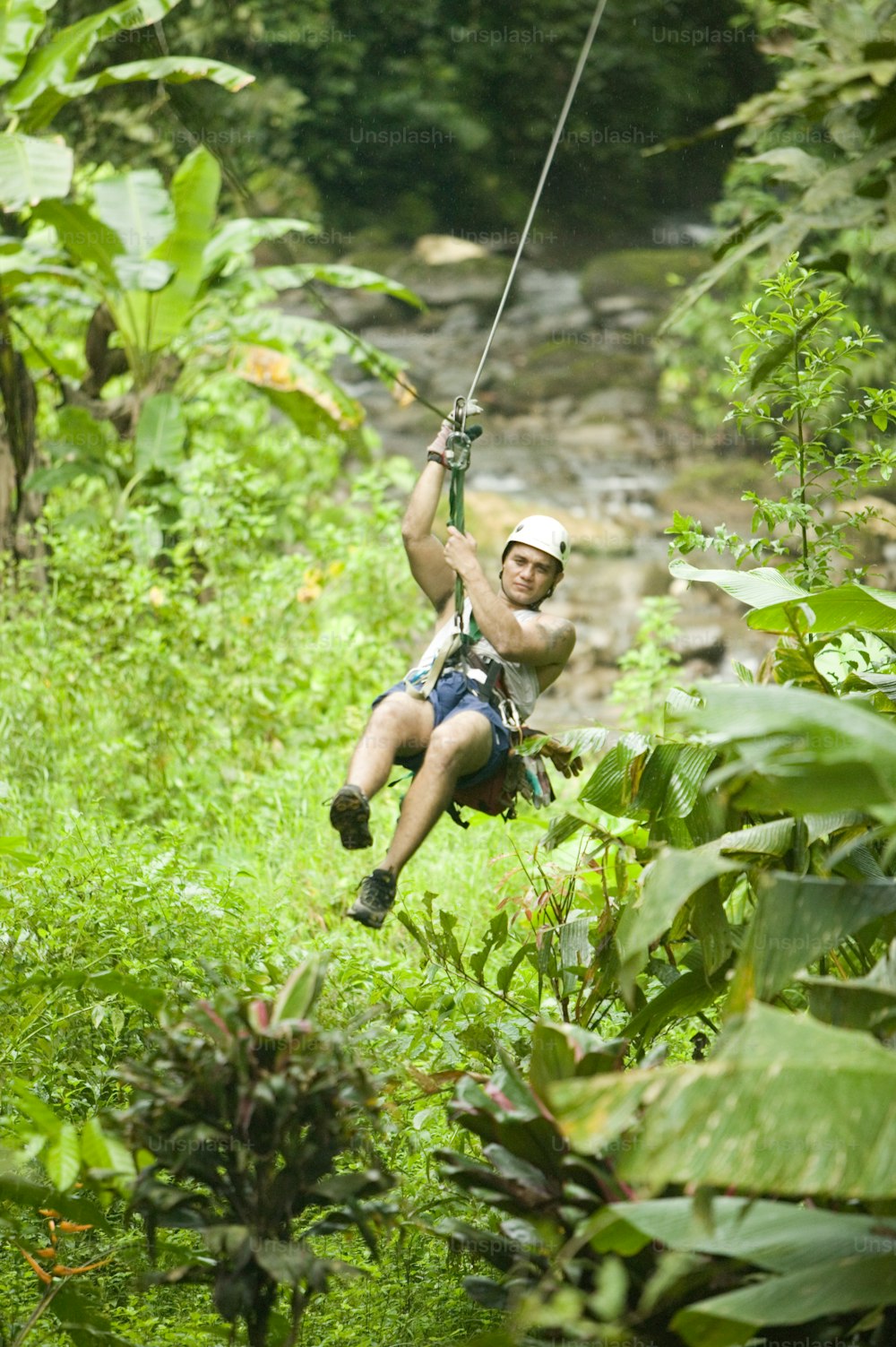 a man riding a zip line in the jungle